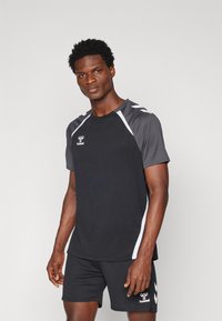 Zwarte shirt met korte mouwen met grijze accenten en witte strepen, voorzien van een logo op de voorkant. In combinatie met zwarte shorts en een gladde textuur.
