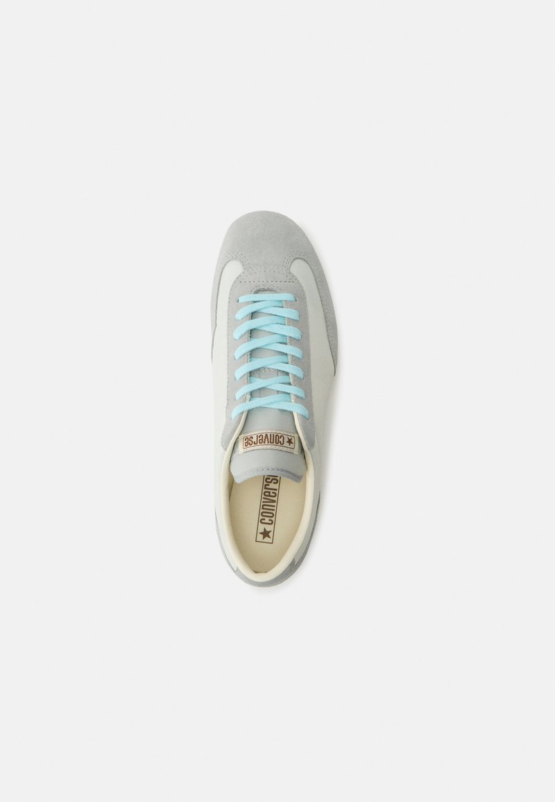 Scarpa da ginnastica Converse grigia e bianca con lacci blu, punta in suede e soletta con marchio, vista dall'alto su sfondo bianco.
