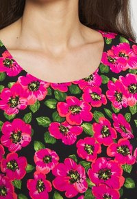 Kwiatowa sukienka z intensywnie różowymi kwiatami i zielonymi liśćmi na czarnym tle. Wycięcie typu scoop i krótkie rękawy, miękka faktura tkaniny.
