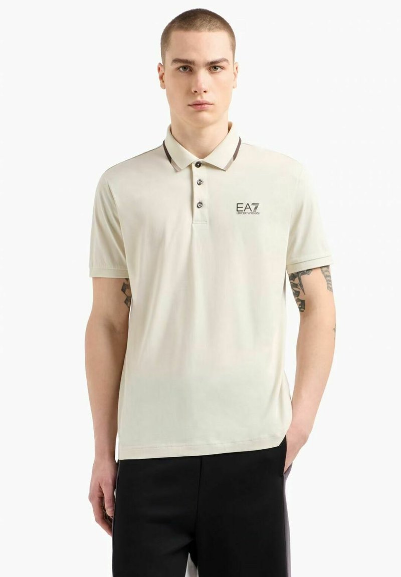 Polo shirt verde chiaro con colletto, tre bottoni e logo stampato sul lato sinistro del petto. Presenta maniche corte e una superficie liscia.
