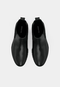 Černé kotníkové boty z hladké kůže s kulatou špičkou, elastickými bočními panely a poutky pro snadné nazutí. Měkká vnitřní podšívka.
