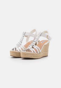Sandali wedges bianchi con design a strappe intrecciate e suola in jute espadrille. Chiusura con fibbia sulla cinghia alla caviglia per una vestibilità regolabile.