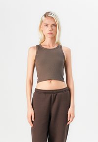 Brun ribbet crop top med rund halslinning, kombinert med matchende brune joggebukser med elastisk liv og avslappet passform.