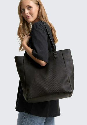 Schwarze gerippte Tragetasche mit doppelten Griffen, aus strukturiertem Material gefertigt, mit einem geräumigen Design und minimalistischen Stil.