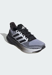 Gray and black athletic shoe with a textured mesh upper, three white stripes, and black laces. Features a cushioned gray sole.