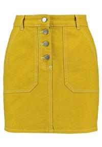 Jupe en denim jaune avec fermeture à boutons sur le devant, cinq poches et coutures blanches contrastées. Conception courte et ajustée avec une finition soignée.