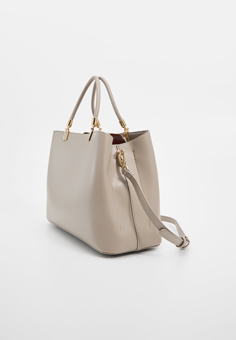 Sac à main en cuir beige avec une forme structurée, deux poignées supérieures, une bandoulière amovible et des accents en métal doré. Texture lisse, design minimaliste.