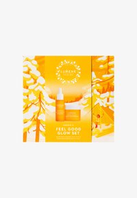 Le set Lumene Nordic-C Feel Good Glow se présente dans une boîte jaune vif, contenant une bouteille d'essence orange et un pot de crème hydratante blanche.