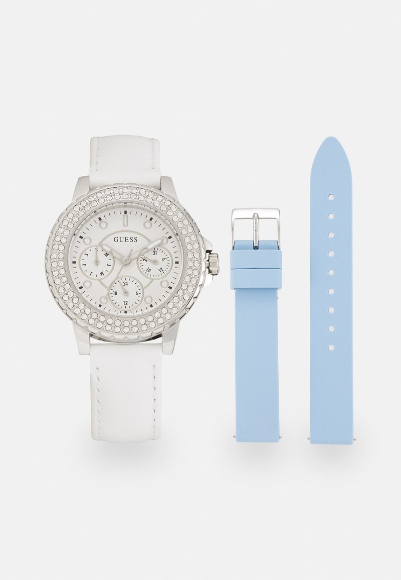 Relógio prateado com pulseira de couro branco; mostrador com detalhes em cristal e três submostradores; inclui uma pulseira de silicone azul claro.