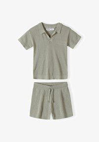 Conjunto de polo de punto de manga corta color verde claro y pantalones cortos a juego de punto con cintura ajustable con cordón, mostrado extendido sobre un fondo blanco.