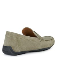 Mocasines de ante en gris claro con punta redondeada, detalles de costura, diseño sin cordones y suela de goma texturizada que presenta el logo de GEOX.