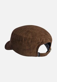 Gorra de pana marrón con corona redondeada y visera plana. Cuenta con una correa trasera ajustable y una etiqueta de marca sutil en el costado.