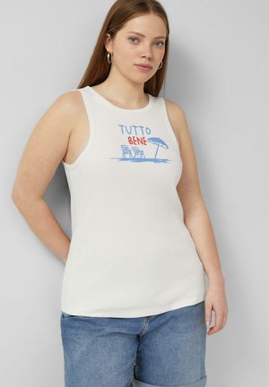 Jeune femme aux longs cheveux portant un débardeur blanc avec le texte « TUTTO BENE » et un motif de chaises de plage avec parasol, associée à un jean bleu.