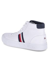 Zapatilla alta de piel blanca con detalles en azul marino, que presenta rayas rojas y azul marino en el costado. Detalle del logo en el talón y suela texturizada.