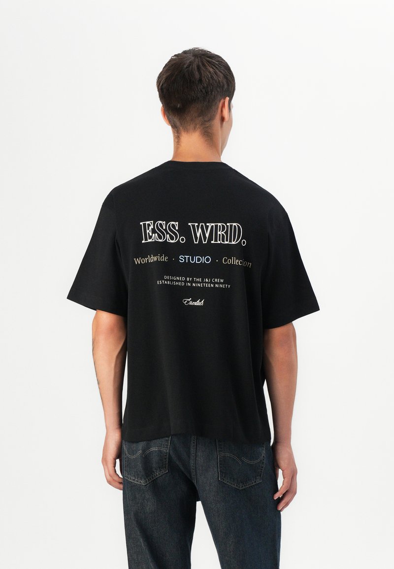 Sort bomulds T-shirt med korte ærmer, med hvid tekst på bagsiden, inklusive "ESS. WRD." og yderligere brandingdetaljer.