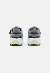 Chaussures de sport grises et noires avec un dessus en mesh, un col rembourré et des détails de semelle extérieure vert lime contrastants. Comprend des languettes à l'arrière.