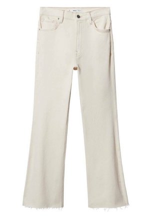 Frau trägt einen langen braunen Mantel, ein schwarz-weiß gestreiftes Hemd, cremefarbene Jeans in verkürzter Länge und braune Wildleder-Stiefeletten mit Blockabsätzen.