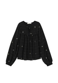 Blouse noire à manches longues avec un col rond et un détail de nœud, ornée de motifs d'étoiles brodés en argent sur un tissu texturé.