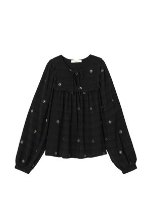 Blouse noire à manches longues avec un col rond et un détail de nœud, ornée de motifs d'étoiles brodés en argent sur un tissu texturé.