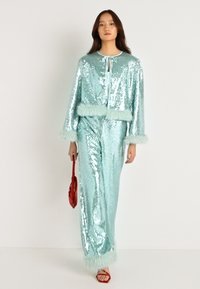 Conjunto de loungewear em sequins na cor aqua clara, com acabamentos em pele falsa nas mangas e na bainha. Top de manga longa com fecho de laço e calças de perna larga a condizer.