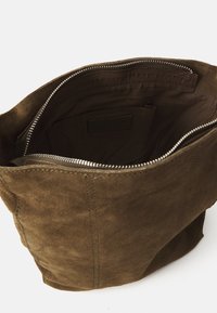 Bolso de ante marrón con una textura suave, cierre de cremallera y un interior espacioso; cuenta con un pequeño bolsillo interior y un diseño elegante.