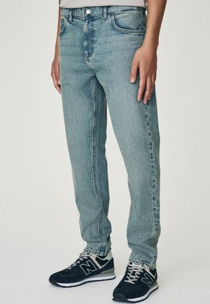 Jean en denim bleu clair avec une coupe droite, présentant un design de poche avant, un léger délavage et une fermeture à bouton métallique standard.