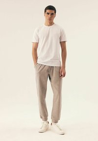 Biała koszulka z krótkim rękawem, szare dresy i białe Sneakersy. Slim fit, miękka tkanina, elastyczny pas, i ściągacze przy mankietach.