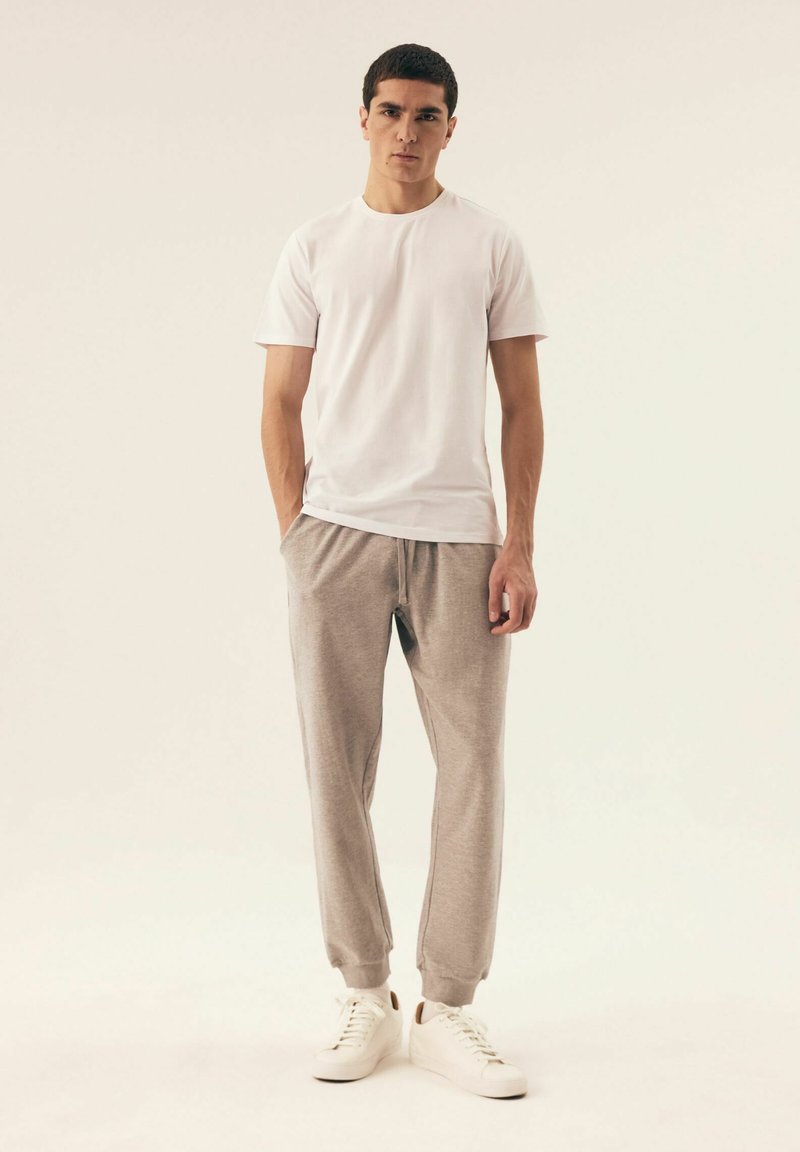 Biała koszulka z krótkim rękawem, szare dresy i białe Sneakersy. Slim fit, miękka tkanina, elastyczny pas, i ściągacze przy mankietach.