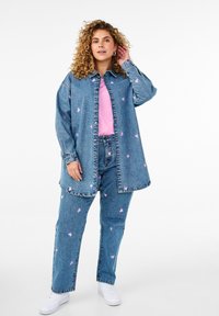 Denimjakk ja püksid komplekt, millel on hele sinine pesu roosa südame mustriga, koos roosa T-särgi ja valgete tossudega.