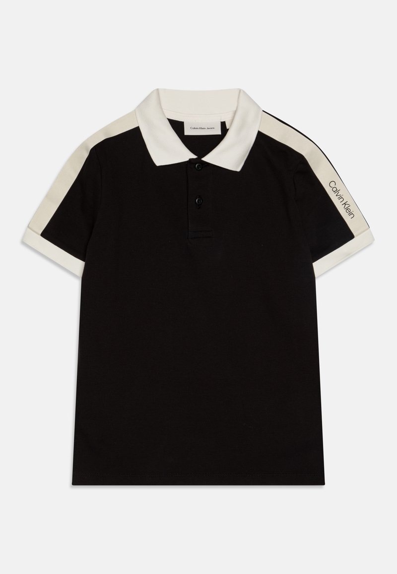 Svart polo shirt med hvit krage og skulderdetaljer. Tre knapper ved halsen. "Calvin Klein Jeans" logo på ermet. Glatt tekstur.