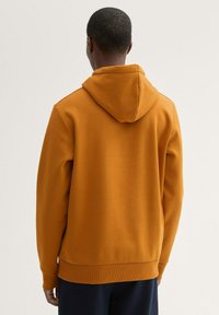 Hanorac portocaliu cu glugă reglabilă și mansete strâmte, având o textură netedă și o croială lejeră. Vedere din spate, fără logo-uri sau elemente de design vizibile.