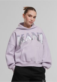 Svijetloplav hoodie s velikim srebrnim logotipom "KANI", prednji džep i rebrasti manžetni. Izrađen je od mekog materijala s opuštenim krojem.