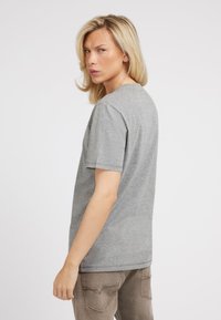 Grå afslappet T-shirt i en blød kvalitet, der har en klassisk rund halsudskæring, korte ærmer og sømløst skulderdesign.