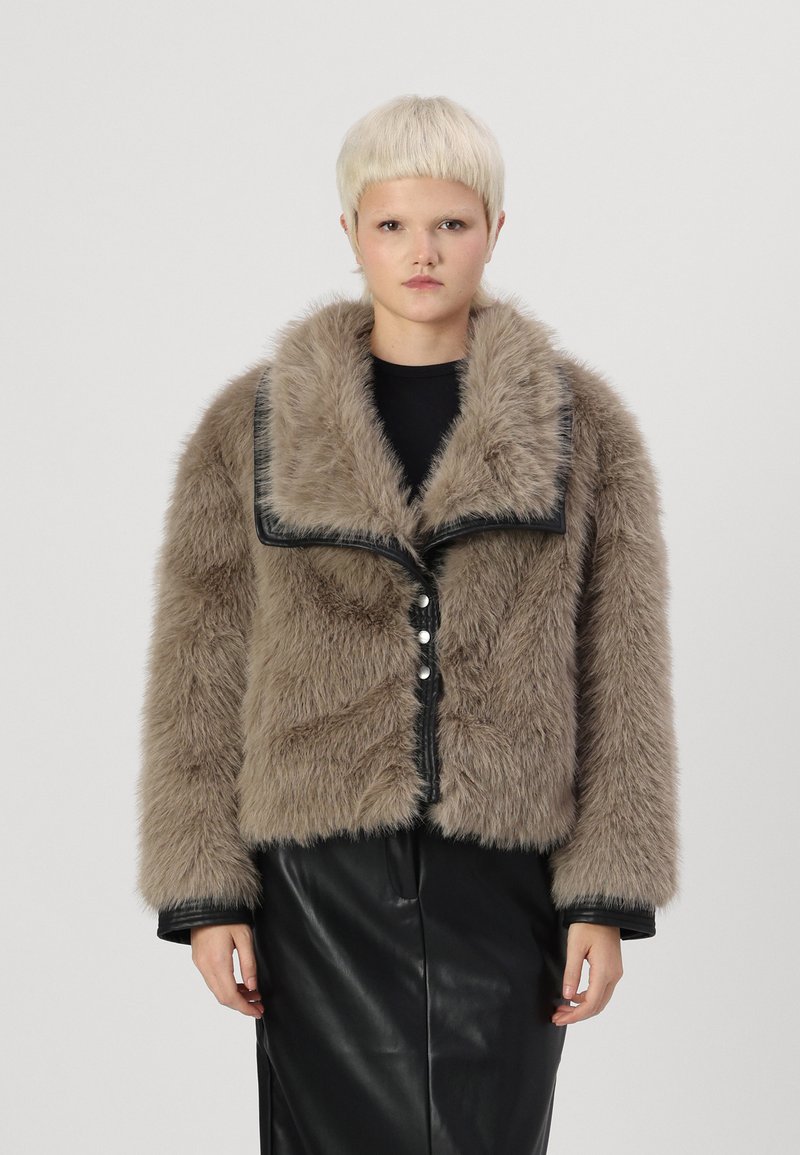 Kunstbont cropped jack in beige met een zwarte leren afwerking. Voorzien van een grote kraag, knoopsluiting en lange mouwen. Soepele textuur.