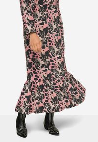 Robe longue à motifs floraux rose et noir avec un ourlet volanté et des manches longues, associée à des bottes chelsea noires à clous.