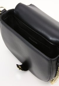Borsa a tracolla in pelle nera con una texture liscia e una tracolla in catena dorata. Presenta una parte superiore aperta e un compartimento interno per riporre gli oggetti.