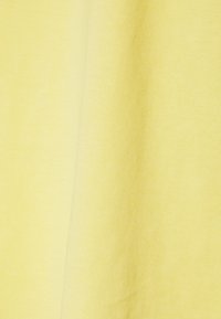 Žlutá bavlněná látka s hladkým povrchem a mírným leskem, která ukazuje jemné šikmé linky v tkaní.