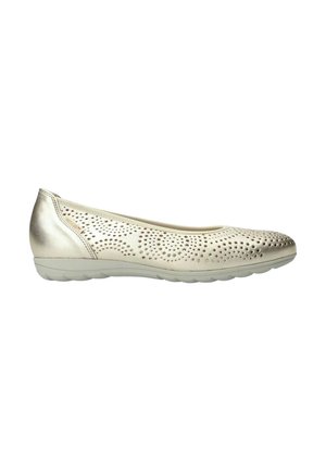 Chaussure plate beige pour femme avec motif perforé sur le dessus et semelle blanche matelassée, vue de profil sur fond blanc.