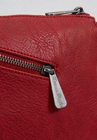 Trousse en cuir rouge texturé avec un tire-zip en argent gravé "Fritzi aus Preußen" sur la poche zippée avant.
