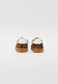 Leooprint sneakers med en overdel i brunt suede, hvide læderdetaljer og såler i gummigummi, med en afrundet tå og lavt design.