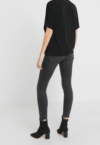 Svart kortärmad topp i kombination med mörkgrå smala jeans och svarta ankelstövlar med klack, med en fransad fåll.