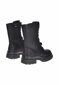 Paio di stivali da combattimento neri in pelle con suole spesse, cerniere laterali e lacci, su uno sfondo bianco.
