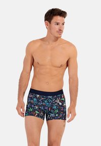 Boxer shorts impresos con una base azul marino y patrones coloridos inspirados en flores y la naturaleza. Tela suave con un diseño ajustado y cinturilla elástica.