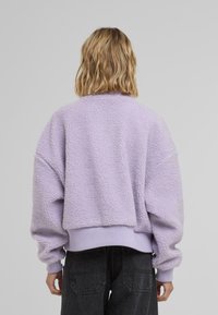 Lila fleece sweater met een cropped ontwerp, textuur oppervlak en geribde manchetten. De achterkant heeft een eenvoudige, ronde halslijn.