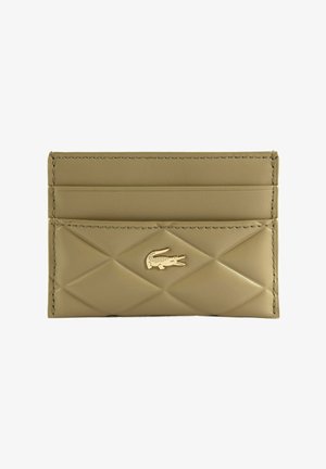 Porte-cartes en cuir beige avec motif matelassé en losanges et logo crocodile doré sur le devant, doté de trois emplacements pour cartes.
