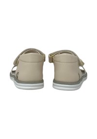 Sandali beige con tomaia in sintetico liscio, cinturini regolabili e suola bianca. Il design include ritagli per la traspirabilità.