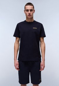 Marineblå bomulds T-shirt med korte ærmer og et lille logo patch på brystet, parret med marineblå shorts med detaljer på siden.