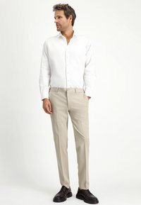 Witte overhemd met knopen, beige broek, donkere schoenen. Slim fit, gladde stof, klassieke kraag en sluiting met knopen aan de voorkant. Eenvoudig, schoon ontwerp.