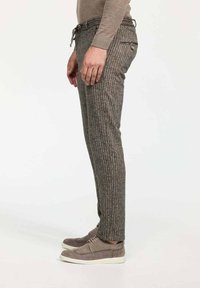 Graue, strukturierte Hose mit vertikal gestreiftem Muster, ausgestattet mit einem Kordelzugbund und Gesäßtaschen, kombiniert mit grauen Schuhen.