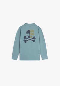 Polo a maniche lunghe di colore azzurro, con una grafica di teschio e ossa incrociate sul retro e il testo "SCALPERS CO." in giallo e blu navy.